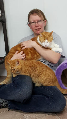 Romona sitting on the floor with Candy and Paul on her lap, Paul is a big orange cat and Candy is a little orange cat
